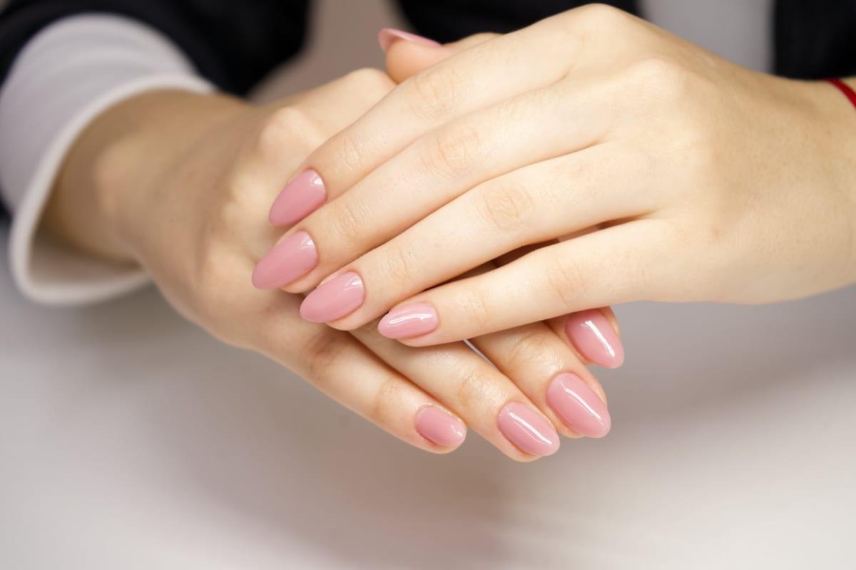 Manicura rosa con acabado brillante, detalle de manos